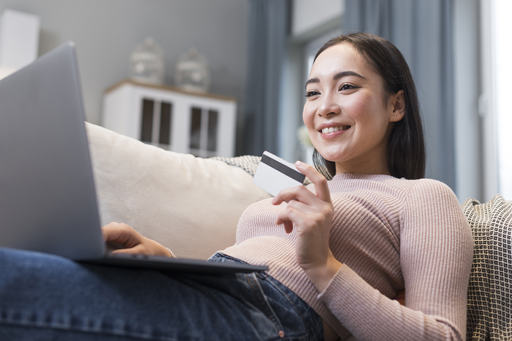 low-angle-smiley-woman-holding-credit-card-laptop