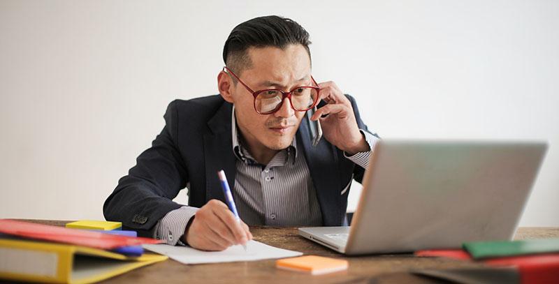 man in phone in front of the laptop